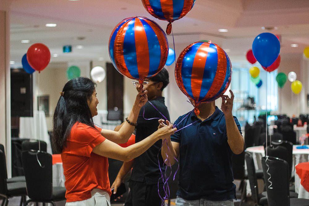 Two people handing out striped foil balloons