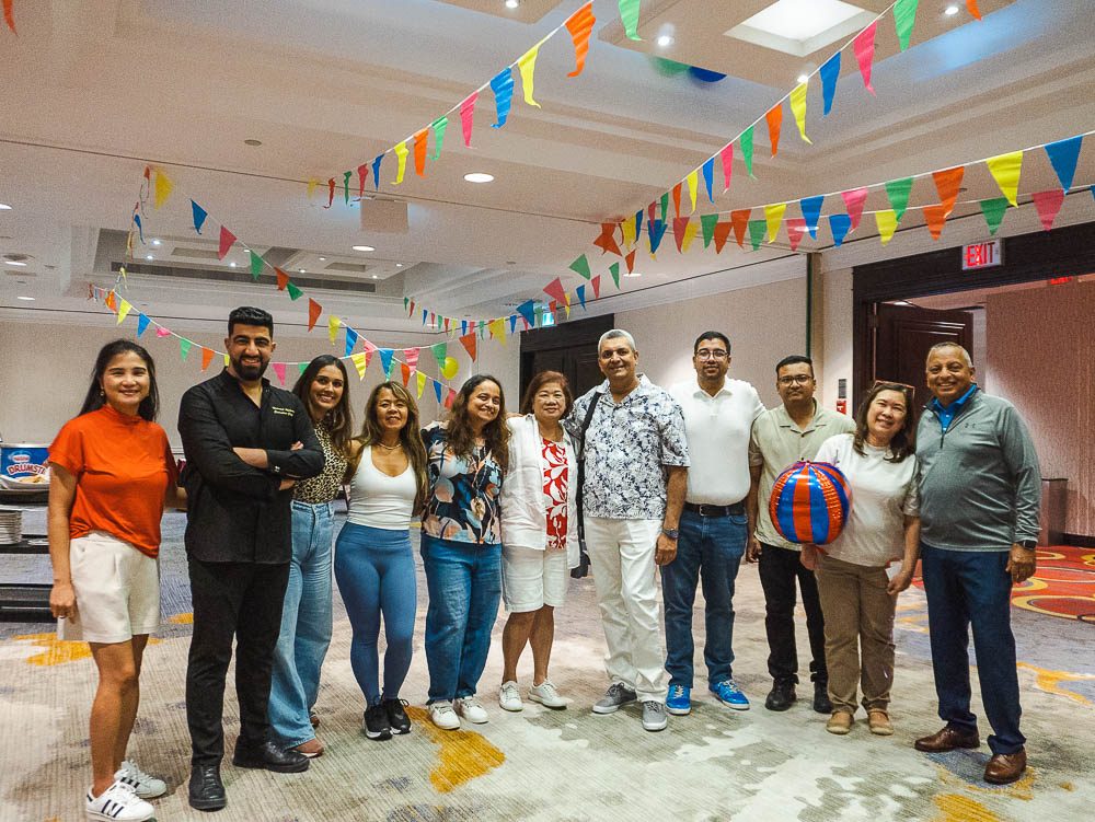 Eleven people posing together under colourful bunting