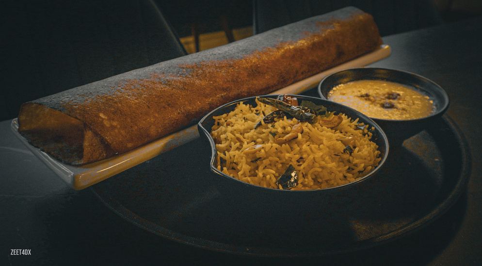 Masala dosa with rice and curry on a dark table