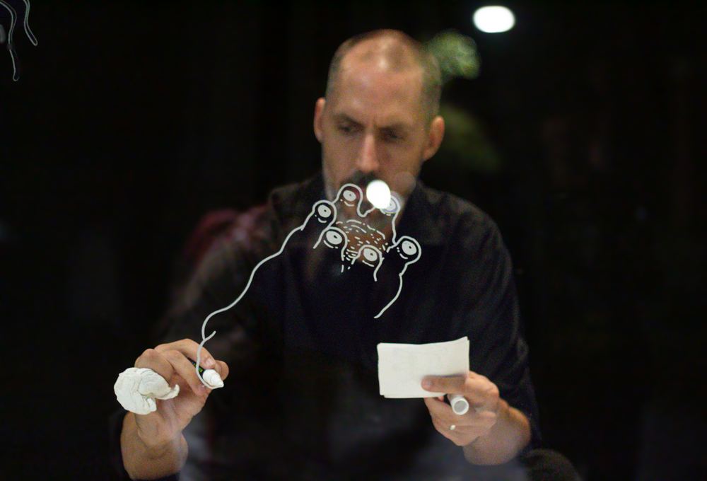 Man holding a small glass sculpture and a card in low light