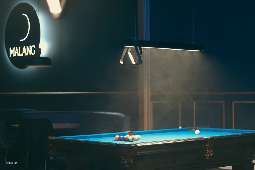 Dark lounge with a pool table under hanging lights
